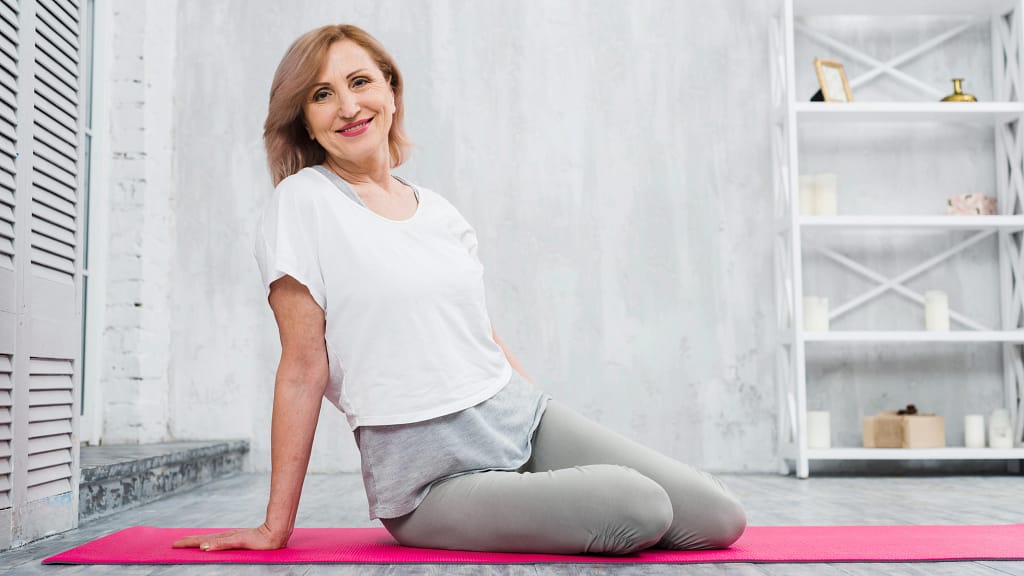 A smiling woman sitting on her yoga mat, showing a relaxed moment after a beginner yoga class.