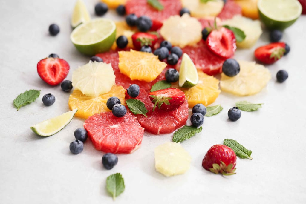 A vibrant mix of citrus slices, berries, and fresh mint leaves.
