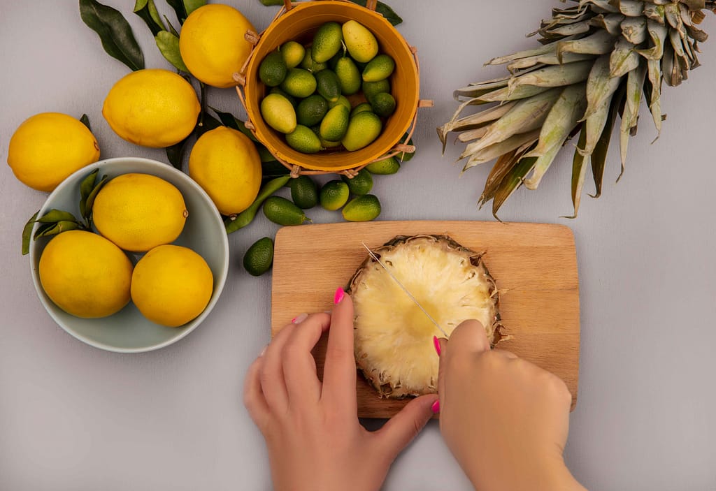 Hands cutting pineapple, a fresh start for Pineapple for Weight Loss meals.