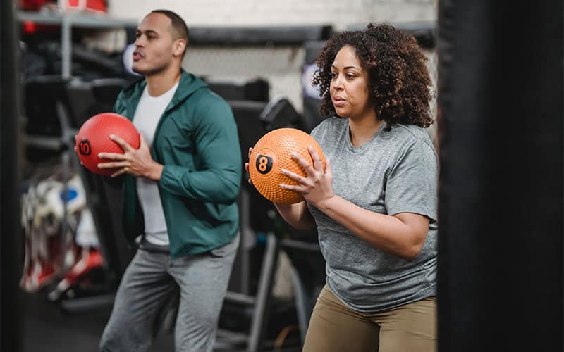 Two people pushing their limits with medicine ball exercises in the gym.