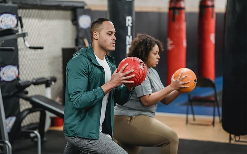 The trainer and trainee are exercising with two balls